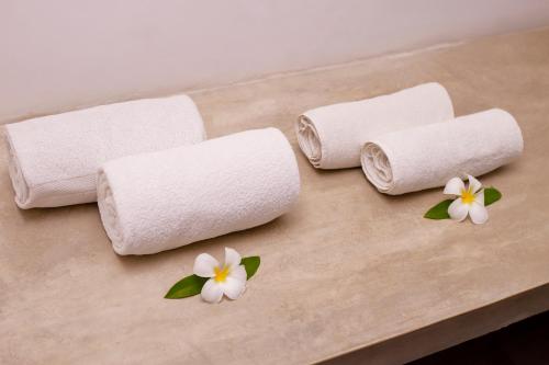 three rolls of toilet paper on a table with flowers at St.Lachlan Hotel & Suites in Negombo