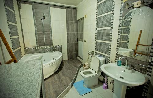 a bathroom with a toilet and a tub and a sink at Zamalek X Hostel-Nile view in Cairo