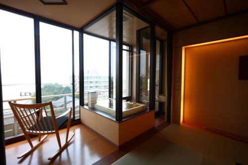 a room with a chair and a large window at Biwako Ryokusuitei in Otsu