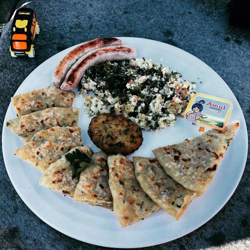 a plate of food with a sausage and pita bread at The Neem in New Delhi