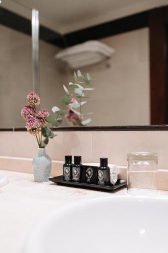 a bathroom counter with three clocks and a vase with flowers at Palacio de Aviles Affiliated By Melia in Avilés