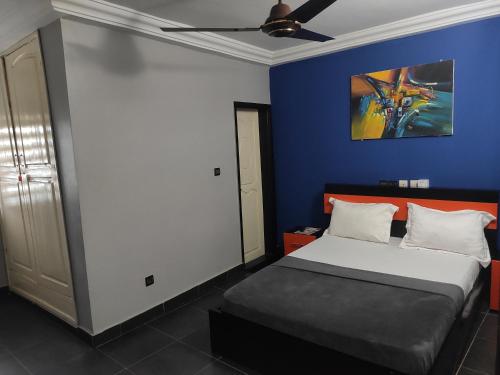 a bedroom with a bed and a blue wall at Standard Double Bed in Royal Blue Guest House and Bar in Lomé