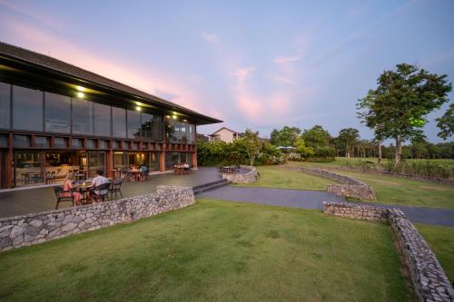 a building with people sitting at tables in a yard at Chatrium Golf Resort Soi Dao Chanthaburi in Ban Thap Sai