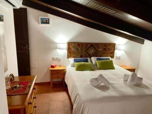 een slaapkamer met een groot wit bed met groene kussens bij Buhardilla de Wallada Córdoba in Córdoba