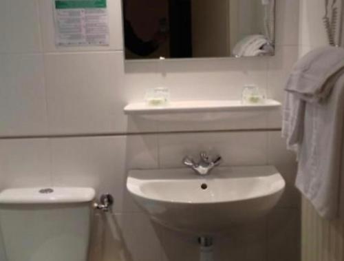 Baño blanco con aseo y lavamanos en HOTEL DE LISIEUX, en Lourdes