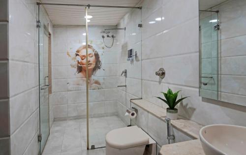 Hotel Ekaa Keys By Rivido - Hosur Main Road, Kudlu Gate في بانغالور: حمام مع دش مع وجه امرأة على الحائط
