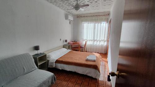 1 dormitorio con cama, sofá y ventana en Pensión Benavente AP-7 3 min - Playa 5 min coche, en Moncófar