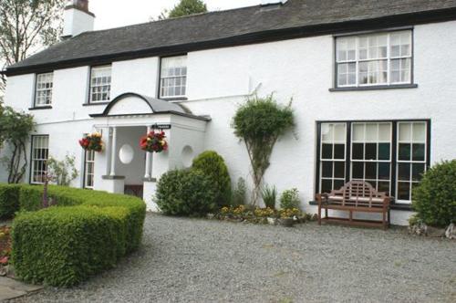a white house with a bench in front of it at Old School House - with private onsite parking in Hawkshead