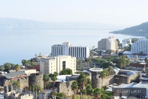an aerial view of a city with buildings and the ocean at YalaRent La Mera- Suits Hotel with Sea of Galilee views in Tiberias