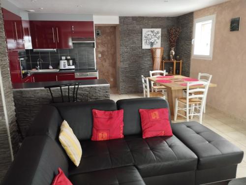 sala de estar y cocina con sofá negro y almohadas rojas en L'estanco, en Vieille-Brioude