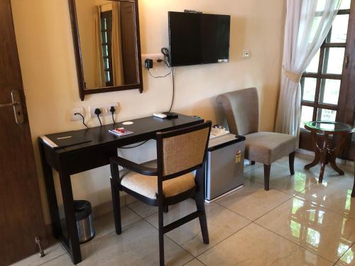 a room with a desk with a chair and a television at The Neem in New Delhi