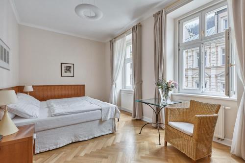 ein Schlafzimmer mit einem Bett, einem Tisch und einem Stuhl in der Unterkunft Hotel Palatin in Karlsbad