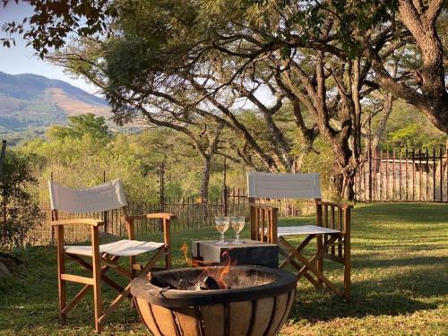two chairs and a table and a fire pit in a yard at Crocodile Sands River Lodge in Nelspruit