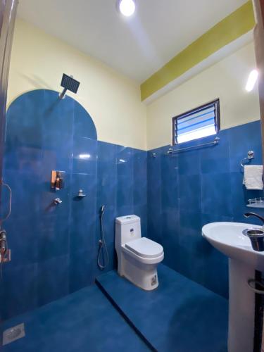 bagno blu con servizi igienici e lavandino di Hotel Greenlight a Chitwan