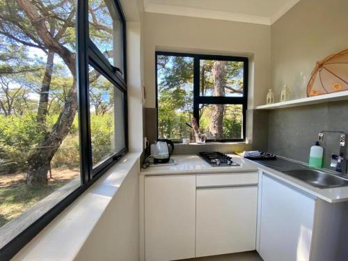 a kitchen with white cabinets and a large window at Crocodile Sands River Lodge in Nelspruit