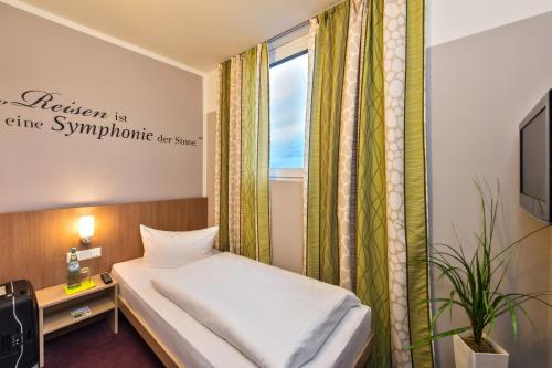 a small bedroom with a bed and a window at Hotel Mainstation in Frankfurt/Main