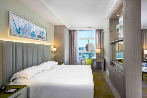 Beach Rotana – All Suites في أبوظبي: غرفة نوم مع سرير أبيض كبير ومكتب