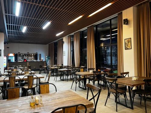 a restaurant with wooden tables and chairs and windows at Didveli Gallery B-211 in Bakuriani