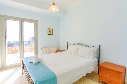 1 dormitorio con cama blanca y ventana grande en Villa Kalamia en Kalámi