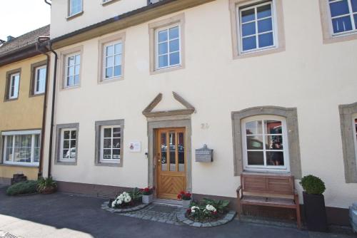 um edifício com uma porta de madeira e um banco em Ferienwohnung im Hofratshaus Bartenstein em Ettenhausen