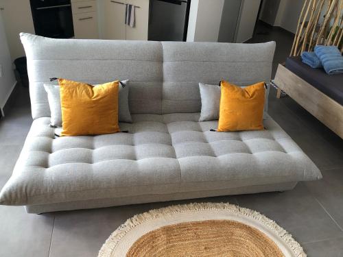 eine graue Couch mit zwei orangenen Kissen drauf in der Unterkunft Studio Kooka nui - Private apartment in Papeete