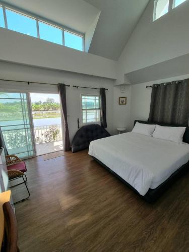 a bedroom with a white bed and a large window at MonMin Farmstay in Ban Mae Cho