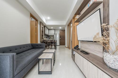 a living room with a couch and a flat screen tv at Grande Valore Hotel Cikarang in Cikarang