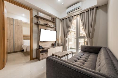 a living room with a couch and a flat screen tv at Grande Valore Hotel Cikarang in Cikarang
