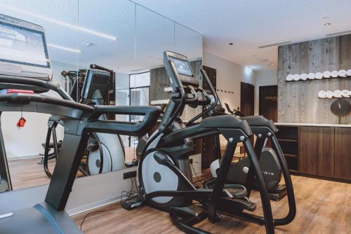 a gym with two treadmills and exercise bikes at GLEMM by AvenidA Superior Hotel & Residences in Saalbach Hinterglemm