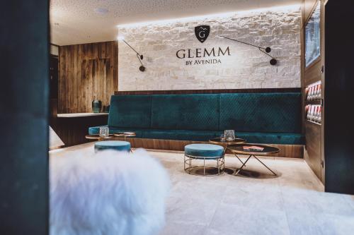 a lobby with a green couch and two chairs at GLEMM by AvenidA Superior Hotel & Residences in Saalbach Hinterglemm
