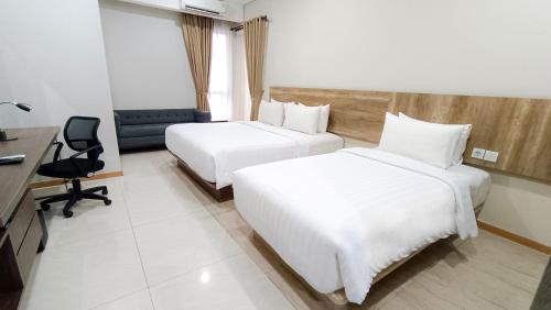 a hotel room with two beds and a desk at Grande Valore Hotel Cikarang in Cikarang