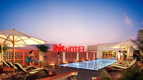 a hotel with a swimming pool and people standing around it at ibis Jaipur City Centre - An Accor Brand in Jaipur