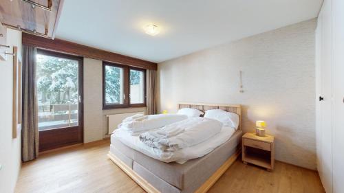 Schlafzimmer mit einem Bett mit weißer Bettwäsche und einem Fenster in der Unterkunft Lovely apartment with a view - accessible by skis in Crans-Montana