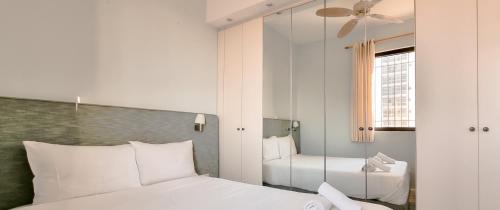 1 Schlafzimmer mit 2 weißen Betten und einem Spiegel in der Unterkunft BnBIsrael apartments - Daniel Royal in Tel Aviv