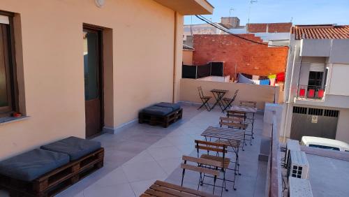 Un balcón con sillas y mesas en un edificio en Pensión Benavente AP-7 3 min - Playa 5 min coche, en Moncófar