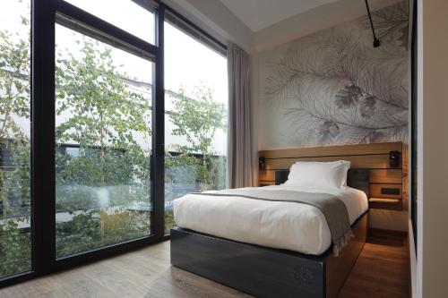a bedroom with a bed and a large window at VERSOVERDE HOTEL Alzaia Naviglio Grande in Milan