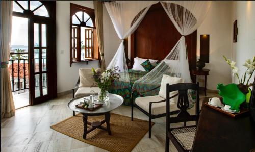 sala de estar con cama, mesa y sillas en The Seyyida Hotel and Spa, en Zanzíbar