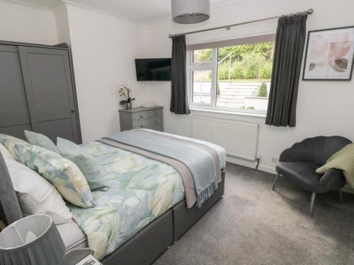 a bedroom with a bed and a window and a chair at Westwinds in Tenby
