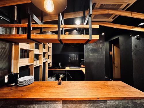 uma cozinha com uma mesa de madeira num quarto em Namba Guesthouse HIVE em Osaka