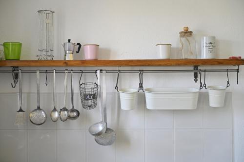 a kitchen with a shelf with utensils on the wall at Casa Aurora con giardino in Bari Sardo