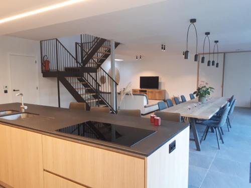 a kitchen and living room with a table and a staircase at Fluithoekhoeve in Koksijde