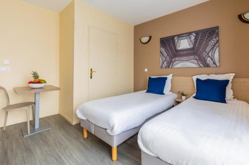 two beds in a room with a desk and a table at Zenitude Hôtel-Résidences Magny-les-Hameaux in Magny-les-Hameaux