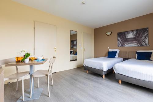 馬尼萊阿莫的住宿－Zenitude Hôtel-Résidences Magny-les-Hameaux，酒店客房设有两张床和一张桌子。