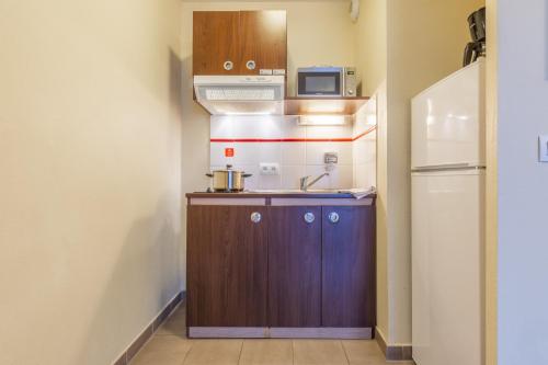 a small kitchen with a sink and a refrigerator at Zenitude Hôtel-Résidences Magny-les-Hameaux in Magny-les-Hameaux