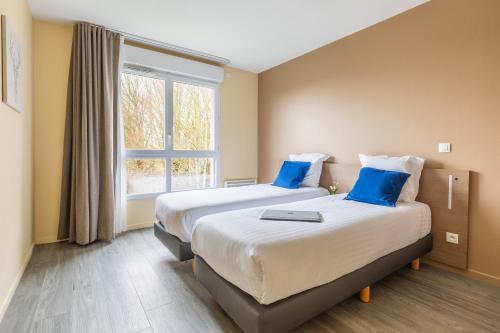 a hotel room with two beds and a window at Zenitude Hôtel-Résidences Magny-les-Hameaux in Magny-les-Hameaux