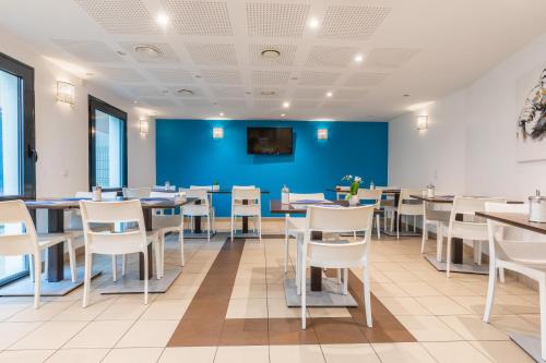 a dining room with tables and chairs and a blue wall at Zenitude Hôtel-Résidences Magny-les-Hameaux in Magny-les-Hameaux