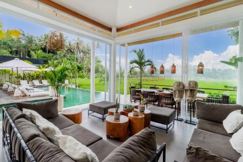 sala de estar con sofá, mesa y piscina en Villa Noemie by BaliSuperHost en Ubud