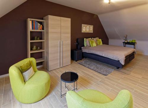 een slaapkamer met een bed, een bank en een stoel bij Wijndomein Zwaeneberg in Voeren