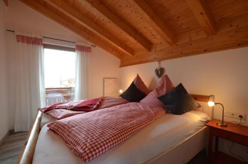 Feriendorf Via Claudia Haus 52 Bunte Kuh في Illach: غرفة نوم بسرير ومخدات حمراء وبيضاء