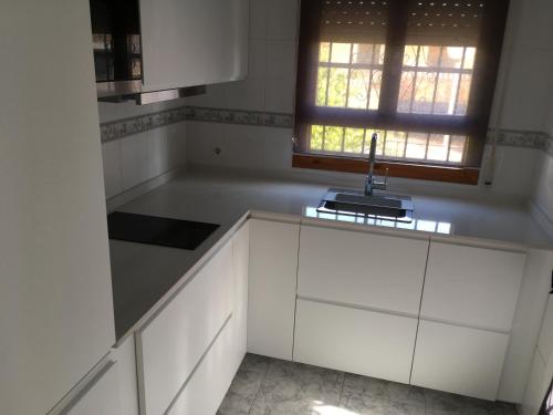 een keuken met witte kasten, een gootsteen en een raam bij Villa South in Ciudad Quesada